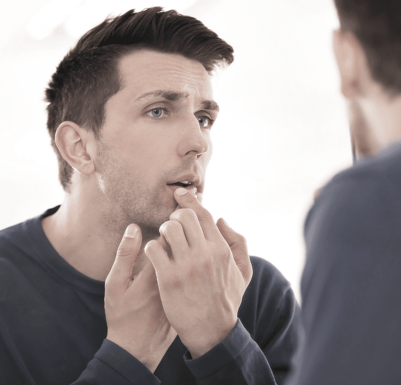 Man looking at mouth in the mirror
