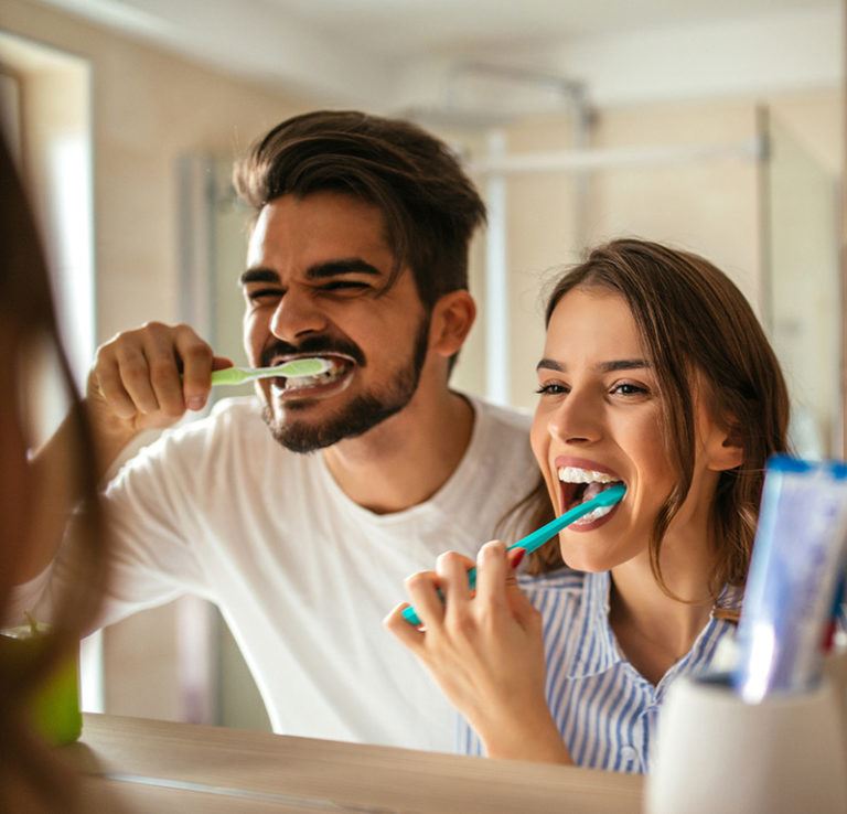 Man and woman brushing their teeth