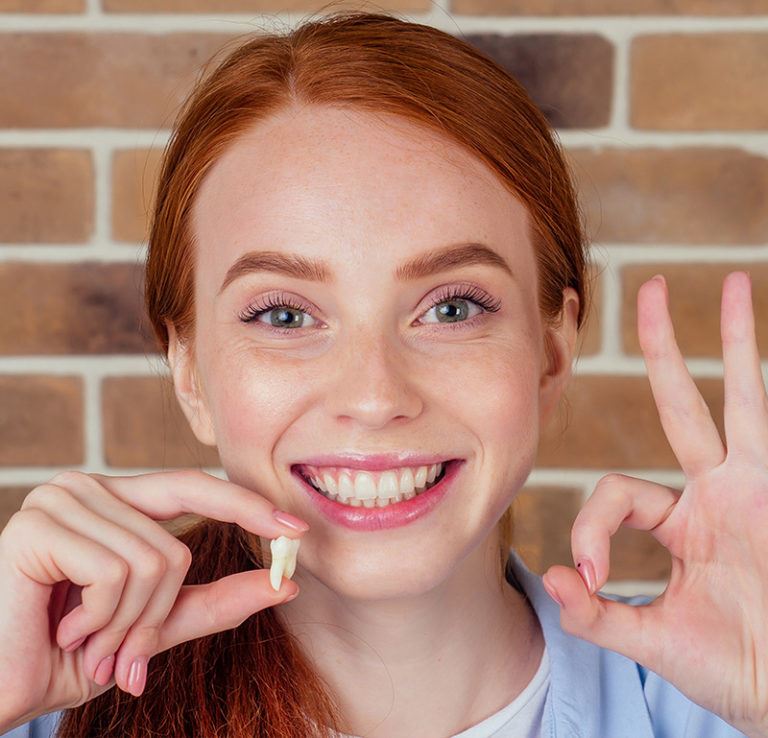 Smiling woman holding a tooth